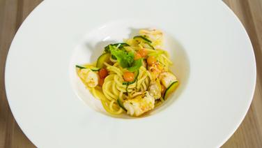 Spaghetti with shrimps, mussels and mint is placed on a plate.  © NDR/SH Magazine 