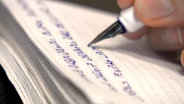In einer Nahaufnahme wird mit einem Füller auf ein Blatt Papier geschrieben. © NDR Foto: NDR Screenshot
