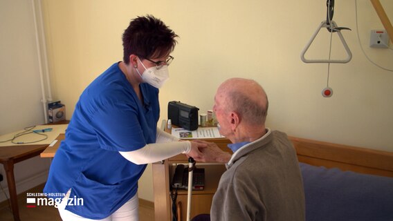 Eine Pflegekraft hilft einem Senioren beim Aufstehen. © NDR 