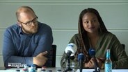 Familienministerin Aminata Touré, (Grüne) sitzt neben einem Mann bei einer Pressekonferenz. © NDR 