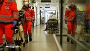 Notfall-Sanitäter gehen durch einen Flur der Notaufnahme am Lübecker UKSH. © NDR 