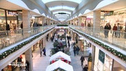 Menschen sind in einem weihnachtlich geschmückten Einkaufszentrum unterwegs. © NDR 