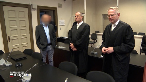 Drei Männer stehen in einem Sall des Hanseatischen Oberlandesgerichts in Hamburg. © NDR 