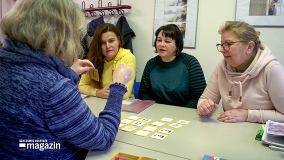 Drei Frauen sitzen an einem Tisch mit einer ehrenamtlichen Lehrerin bei einem Sprachkurs beim Bad Oldesloer Verein Kaktus. © NDR 