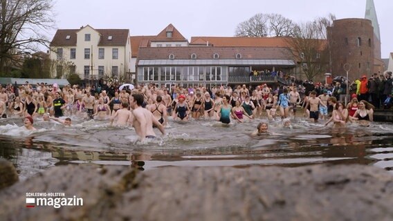 Zahlreiche Menschen stürzen in ein Gewässer im Winder bei der Eisbadewette in Lübeck. © NDR 