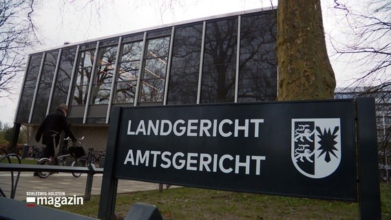 Ein schwarzes Schild mit dem Schriftzug "Landgericht Amtsgericht" steht vor dem Gebäude des Land- und Amtgerichts in Lübeck. © NDR 
