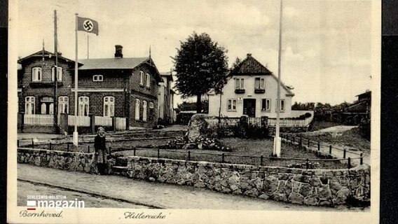 Eine historische schwarz-weiße Aufnahme zeigt ein Mädchen, das neben einem Rasen mit einem Gedenkstein und einer Hitlereiche in Bornhöved steht. © NDR 