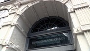 Der Bogen über dem Eingang zum  Buddenbrookhaus-Museum trägt einen Schriftzug aus dunkel-grauen Buchstaben "Buddenbrookhaus". © NDR 