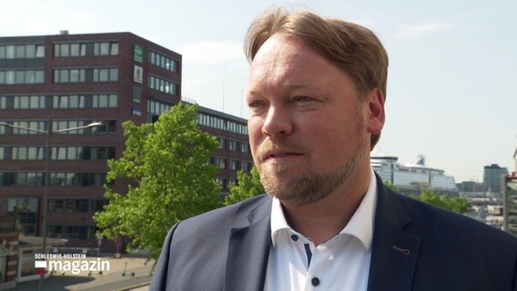 FDP-Landesvorsitzender Oliver Kumbartzky blickt zur Seite bei einem Interview auf der Brücke vor dem NDR-Landesfunkhaus in Kiel. © NDR 