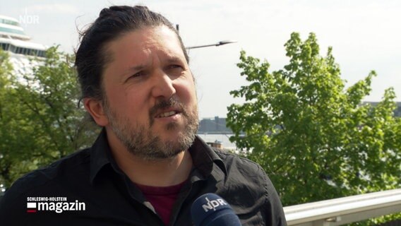 Grünen-Landesvorsitzender Gazi Freitag spricht bei einem Interview nach der Kommunalwahl 2023 in Schleswig-Holstein vor dem Kreuzfahrtterminal in Kiel. © NDR 