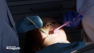 Ein junges Mädchen liegt auf dem Behandlungsstuhl in einem Zahnarztzimmer und wird behandelt. © NDR 