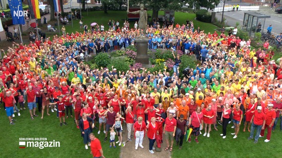 Regenbogen Challenge, Menschengruppe mit farbigen T-Shirts bilden Regenbogenkreis. © NDR Foto: NDR
