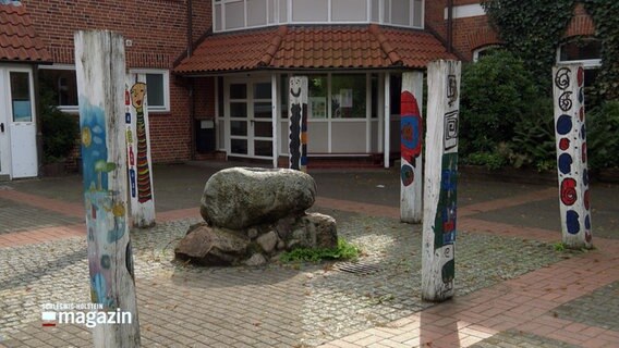 Weißgefärbte und bunt bemalte Holfpfähle stehen vor dem Eingang zum Förderzentrum am Kastanienweg in Bad Segeberg. © NDR 