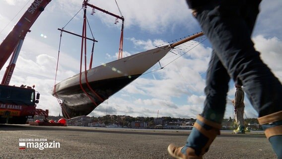 Eine Riesen-Yacht wird in der Berking-Werft von einem mobilen Kran aus dem Wasser gehoben. © NDR 