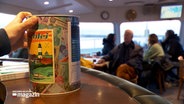 Eine Spardose steht auf einem Tisch im Gruppenraum eines Ausflugsschiffes auf der Schlei. © NDR 