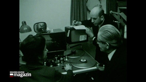 Eine historische Aufnahme aus der Nordschau von 1970 zeigt eine Frau (l.) und zwei Männer (r.) in einem Schnittraum der Firma Nordmark Film an einem Schnitttisch. © NDR 