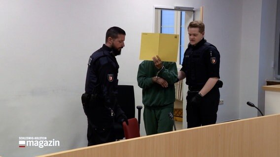 Zwei Justizbeamte führen einen Angeklagten in einen Gerichtssaal am Lübecker Landgericht. © NDR 