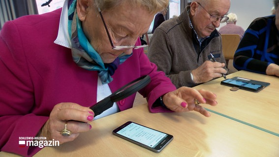 Senioren sitzen an einem Tisch und sind mit ihren Smartphones beschäftigt. © NDR 