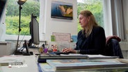 Eine Frau sitzt in einem Büro an einem Arbeitstisch und blickt auf den PC-Monitor. © NDR Foto: Johannes Tran