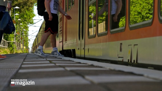Ein junger Mann steigt in eine Regionalbahn in Brokstedt ein. © NDR 