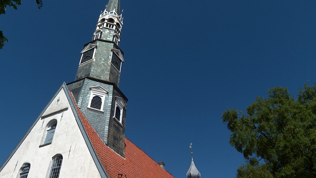 Der Kirchturm der Heider St.Jürgen Kirche ragt nach Sanierung in den blaeun Himmel. 