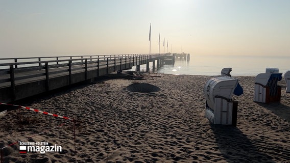 Ein Flatterband am Strand von Dahme hängt vor der Seebrücke. © NDR 