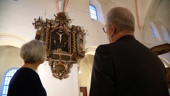Eine Frau und ein Mann blicken auf den Altar in einer Kirche © NDR 