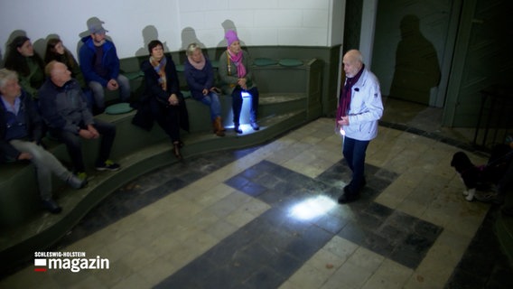 Der Stadtführer Knut Franck steht in einer Kapelle vor einer Gruppe während einer Nachtwanderung durch Flensburg © NDR 