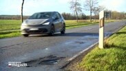 Ein Auto fährt über eine sanierungsbedürftige Landstraße © NDR 