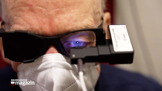 Ein Mann trägt ein Spezialgerät vor seinem Auge © NDR 