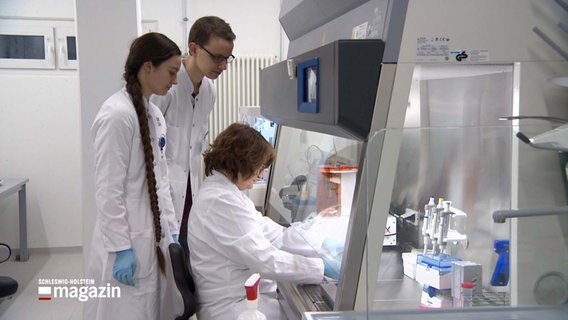 Drei Personen im weißen Kittel stehen in einem Labor © NDR 