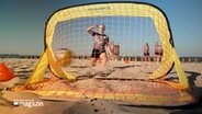 Ein Fussballtor für Beachsoccer steht am Strand, eine Frau schießt einen Ball in das Tor. © NDR Foto: NDR Screenshots