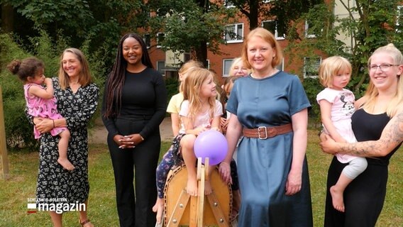 Die Bundesfamilienministerin Lisa Paus (Grüne) und schleswig-holsteinische Familienministerin Aminata Touré (Grüne) stehen mit Kindergartenkindern in einem Garten. © NDR Foto: NDR Screenshots