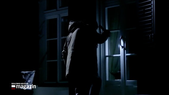 In einer nachgestellten Szene sieht man wie eine Person nachts in ein Haus einzubrechen. © NDR Foto: NDR Screenshots