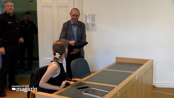 Ein Angeklagter begrüßt seine Verteidigerin im Gericht in Flensburg. Es ist Hendrik Fauer, ein Aktivist der "Letzten Generation" © NDR Foto: NDR Screenshots