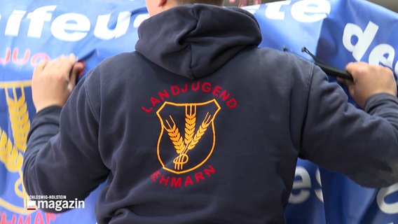 Eine Person trägt einen Pullover, auf dessen Rücken "Landjugend Fehmarn" geschrieben steht. © NDR 