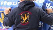 Eine Person trägt einen Pullover, auf dessen Rücken "Landjugend Fehmarn" geschrieben steht. © NDR 