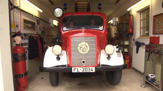 Ein historisches Feuerwehrfahrzeug vom „Förderverein Feuertechnisches Denkmal Dollerup e. V." steht in einer Halle. © NDR 
