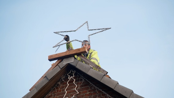 Christian Rösenberg befest einen Stern auf einem Hausdach © NDR 