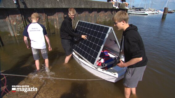 Drei Schüler der Meldorfer Gelehrtenschule testen ein selbstgebautes Rettungsboot im Wasser © NDR Foto: NDR