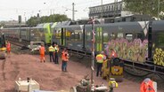 Polizei und Bahnmitarbeiter stehen nach einem Unfall mit einer Oberleitung auf einer Bahnstrecke © NDR 