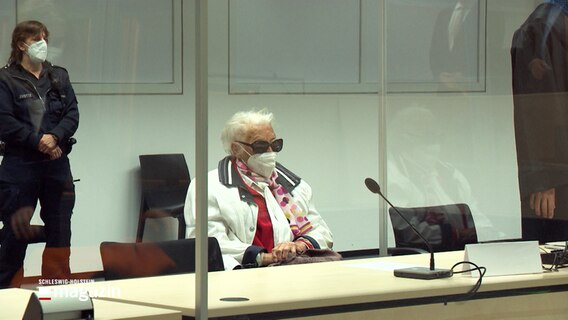 Eine angeklagte ältere Frau sitzt in einem Gerichtssaal. © NDR 