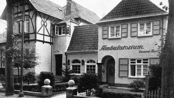 Ein historisches schwarz-weißes Foto zeigt eine Villa mit dem Schild "Ambulatorium" in einer Straße in Ahrensburg. © NDR 