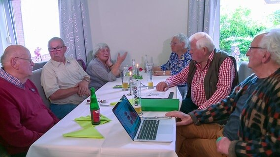 Senioren sitzen an einem Tisch in einem Raum. © NDR 