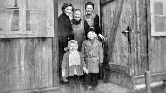 Mütter stehen mit ihren Kindern in der Tür einer alten Holzbaracke. © Sammlung Helmut Dumke 