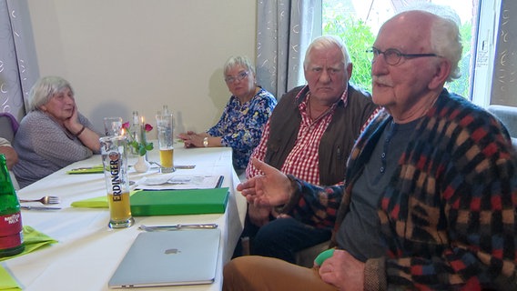 Senioren sitzen an einem Tisch in einem Raum. © NDR 
