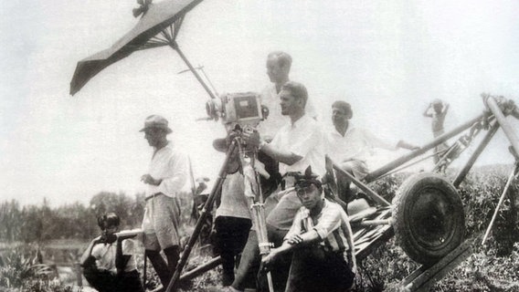 Eine alte Fotoaufnahme zeigt eine Filmcrew im Ausland. © Screenshot 