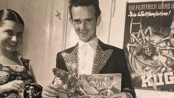 Der ehemalige Artist Oscar Hess alias Don Oscarez auf einem alten Foto vor einem Zirkusplakat. © NDR / SH Magazin 
