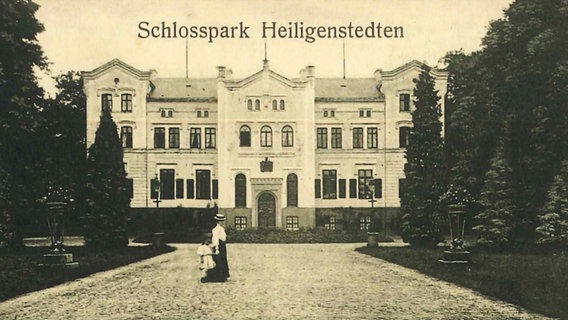 Ein historisches Foto mit der Überschrifft Schlosspark Heiligenstein. Im Vordergrund ist eine Frau mit einem Kind an der Hand auf einem gepflasterten Weg zu sehen, im Hintergrund das Schloss von vorne. © NDR / SH Magazin 