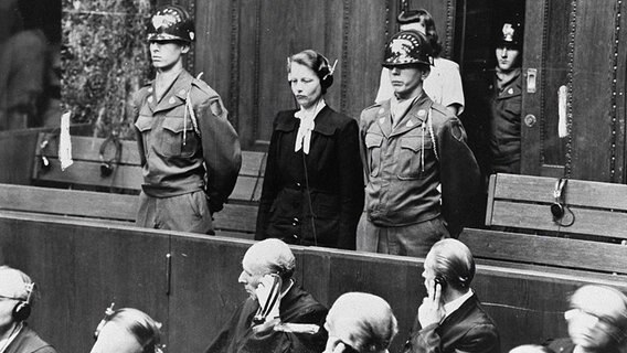 Herta Oberhauser steht vor Gericht neben zwei Polizeibeamten. © NDR 